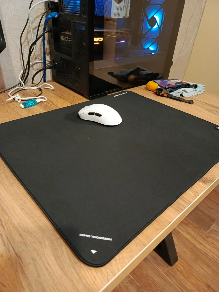 Mouse blanco sobre mouse pad Furycube Zora negro junto a computador gamer